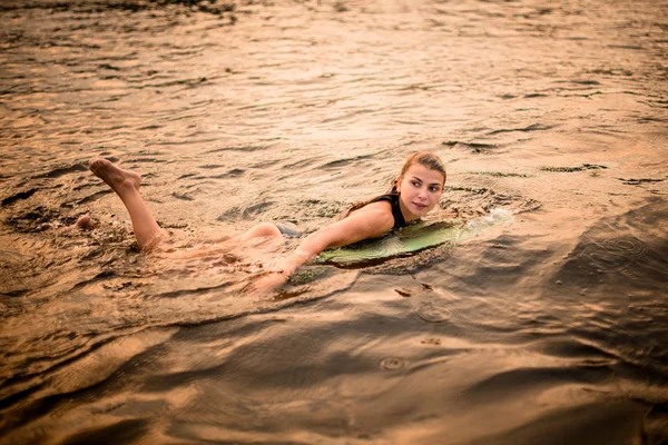Swimming female wakesurfer with a surfboard in the river — Stockfoto