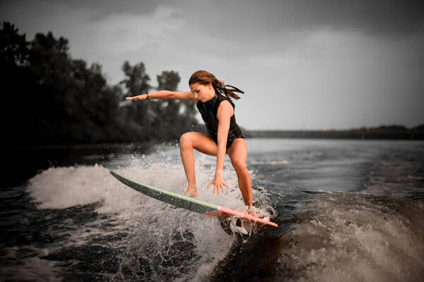 Fitted girl wakesurifing in the river near forest
