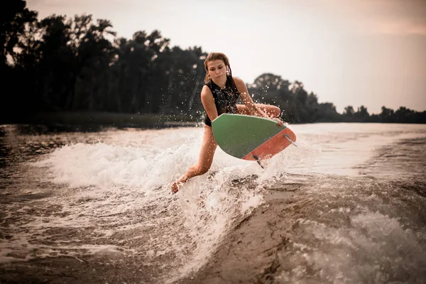 Giovane ragazza wakesurifing e volare nel fiume vicino foresta — Foto Stock