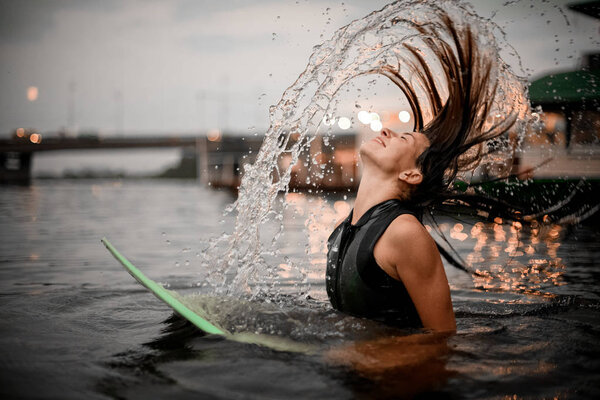 Surfing girl waves her hair in the water