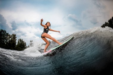 Girl wakesurfer performs stunts on a board clipart