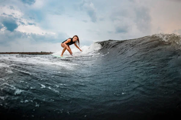 Young girl gliding on a wakeboard in the river near forest — Stock Photo, Image