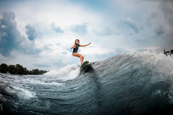 Niña surfea en un wakeboard en el río cerca del bosque —  Fotos de Stock