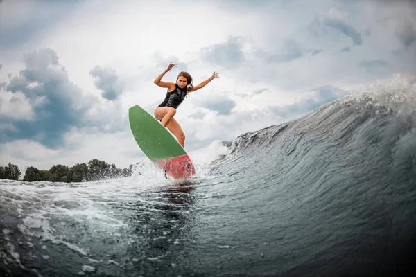 Young girl jumps on a wakeboard in the river near forest — ストック写真