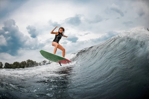 Young girl jumping on a wakeboard in the river near forest — ストック写真