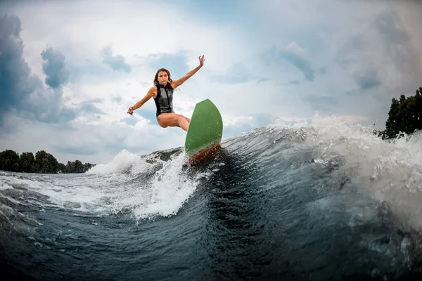 Young girl stunts on a wakeboard in the river near forest — ストック写真