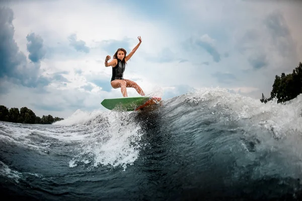 Young girl stunting on a wakeboard in the river near forest — Stock Photo, Image