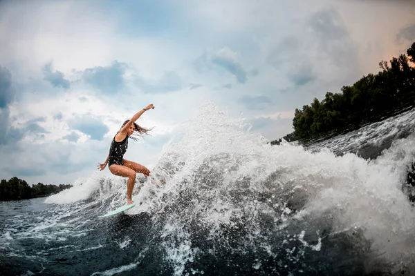 Female wakesurfer performing stunts on a board — ストック写真