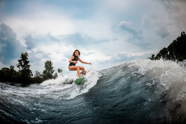 Mulher wakesurfer fazendo acrobacias em uma placa — Fotografia de Stock