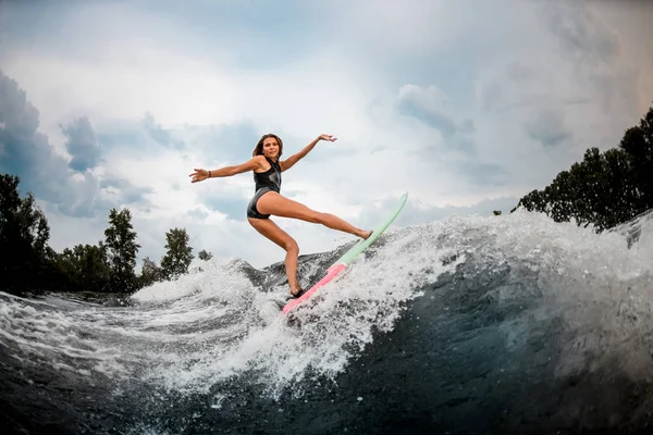 Female wakesurfer does stunts on a board — ストック写真