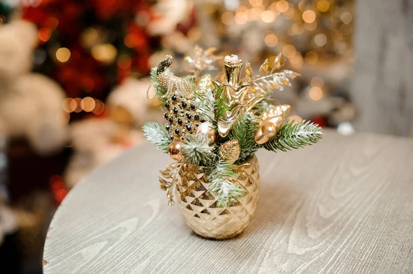 Ваза в форме ананаса золотого цвета с рождественским декором из игрушек и елок — стоковое фото