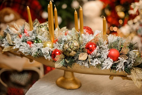 Длинная золотая ваза с рождественским декором из цветов, игрушек и многих золотых свечей — стоковое фото