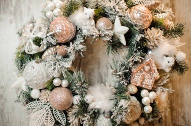 Noel çelengi beyaz ve pembe renkli oyuncaklar, toplar, kasetler ve çiçekler serpiştirilmiş.