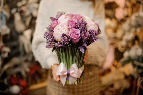 Woman holding a bouquet of tender pink and purple color flowers with green stalks — Stock Photo, Image