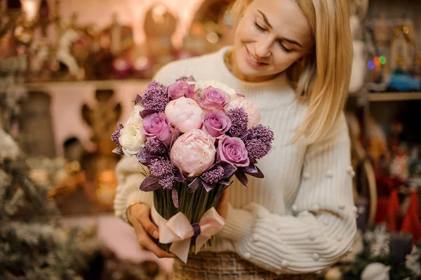 푸른 줄기가 달린 연분홍 과 자주 색 꽃 꽃다발을 들고 있는 미소짓는 여인 — 스톡 사진