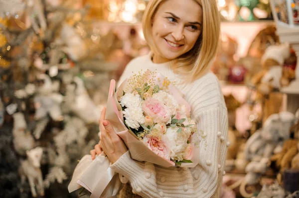 Ragazza sorridente in possesso di un bouquet di rose tenera peonia rosa decorato con rametti e foglie verdi — Foto Stock