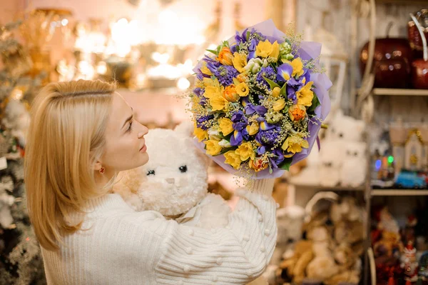 Nő kezében egy kis csokor lila és fehér virágok csomagolva ajándék papír — Stock Fotó