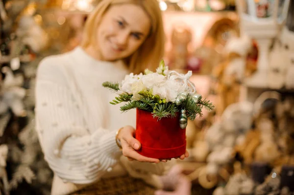 Mosolygó nő kezében egy piros doboz fehér virágok díszített fenyőfa ágak — Stock Fotó