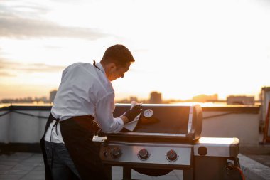 cook man wipes the grill equipment for barbecue clipart