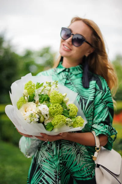 Mujer sonriente sostiene ramo con rosas blancas y hortensias verdes . — Foto de Stock