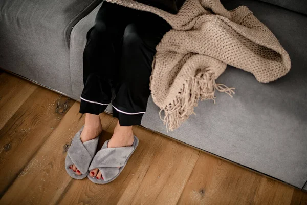 Siyah ipek pijamalı kadın bacakları ve örülü gri terlikler.