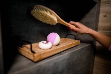 Kadınların elleri banyodaki raflardan banyo fırçası alır..