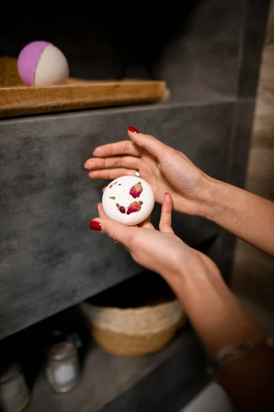 Beau savon avec des pétales dans les mains de la femme dans la salle de bain. — Photo