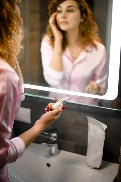 Wanita cantik muda melihat bayangannya di cermin kamar mandi — Stok Foto