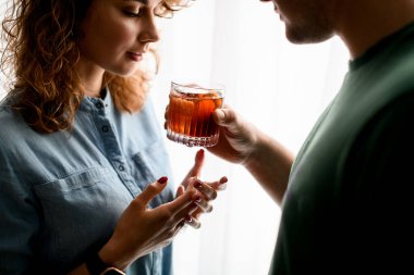 Erkek, genç ve güzel bir bayana kokteyl ile bardağı düzgünce uzatır..
