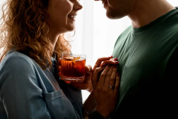 Pria dan wanita tersenyum berdiri berdekatan dan memegang satu gelas dengan koktail. Stok Foto Bebas Royalti