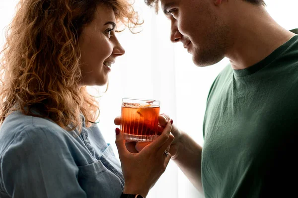 Pria dan wanita tampan berdiri berdekatan dan memegang satu gelas dengan koktail. Stok Foto
