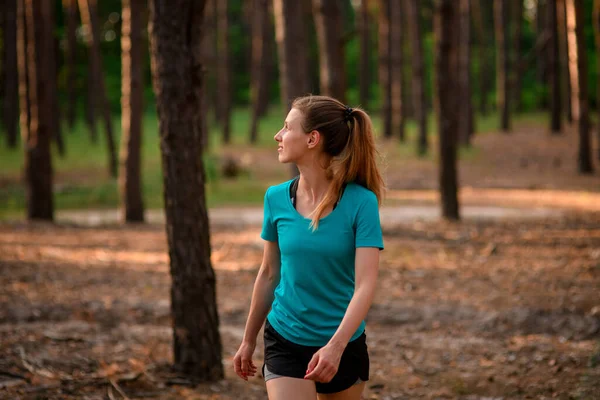 Jonge mooie vrouw loopt in het bos en kijkt weg. — Stockfoto