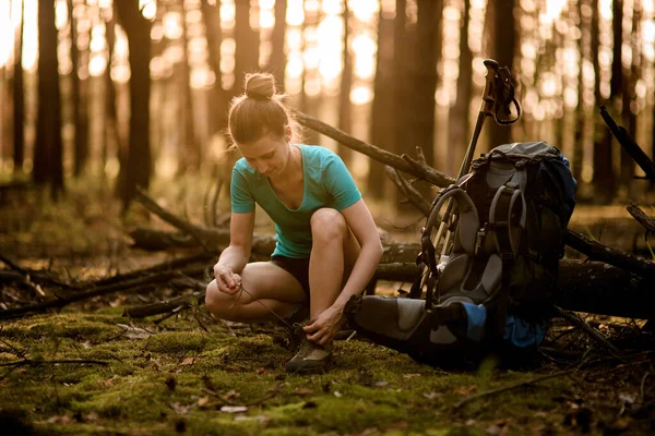 Ung kvinna i skogen band skosnören på skor. — Stockfoto