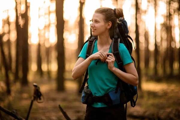 Vue de jeune femme souriante avec sac à dos de sport qui marche en forêt — Photo