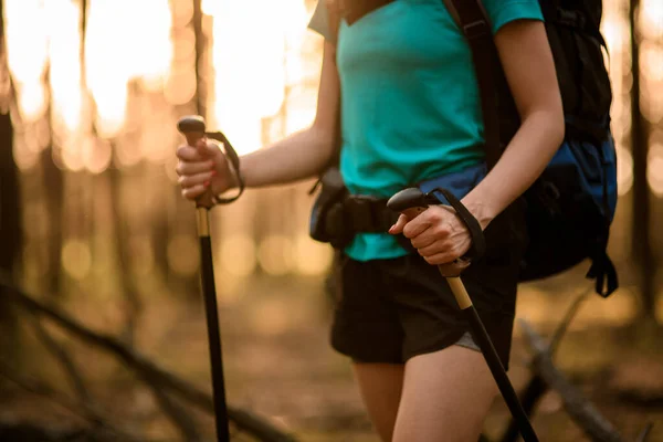 Gros plan de la jeune touriste avec sac à dos et des bâtons dans ses mains dans la forêt. — Photo