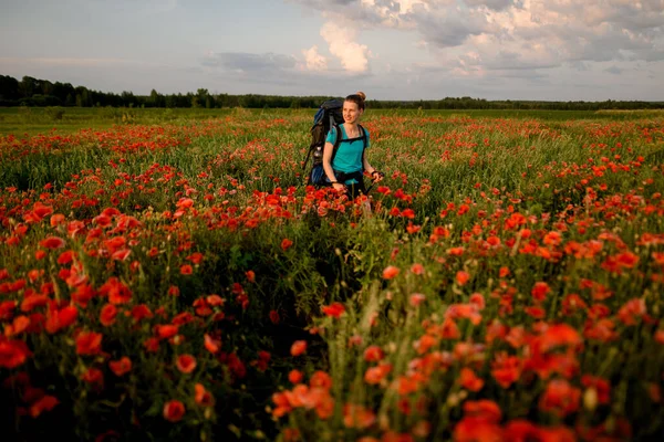 Visão de turista jovem que caminha no campo de papoilas vermelhas . — Fotografia de Stock