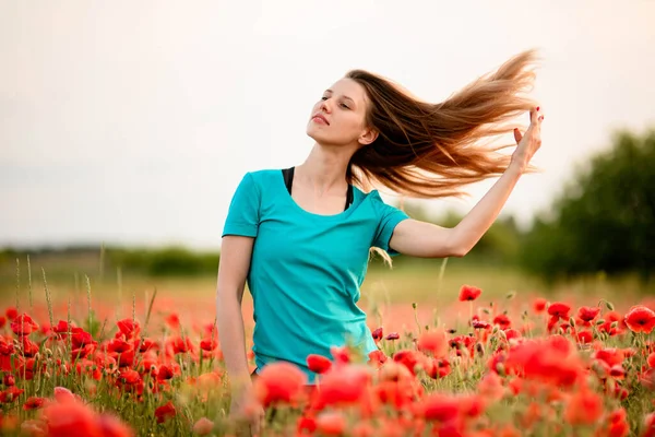 Молодая женщина с длинными волосами, стоящая на поле с красными маками . — стоковое фото