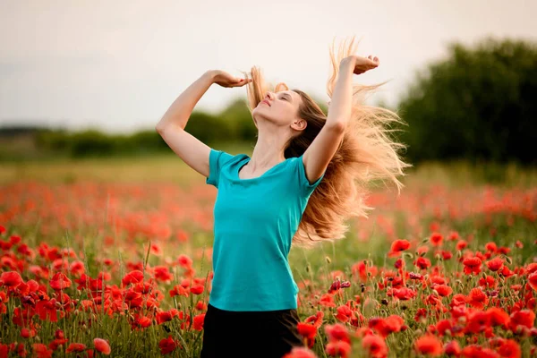 Beautiful young woman with head thrown back and flowing hair who standing on field with red poppies. — Stock Photo, Image