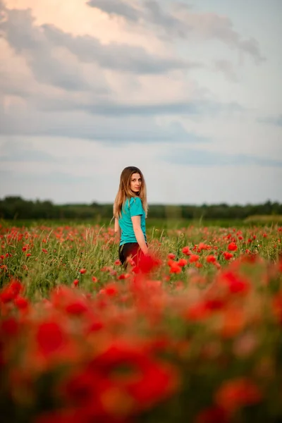 Ansicht der schönen jungen Frau mit umgedrehtem Kopf, die auf einem Feld mit roten Mohnblumen steht. — Stockfoto