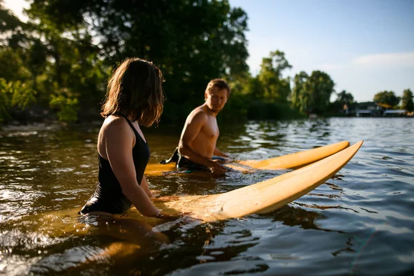 Jovem homem e mulher estão sentados em suas pranchas de surf na água — Fotografia de Stock