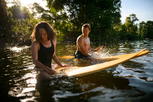 Hombre y mujer están sentados en sus tablas de surf en el agua —  Fotos de Stock