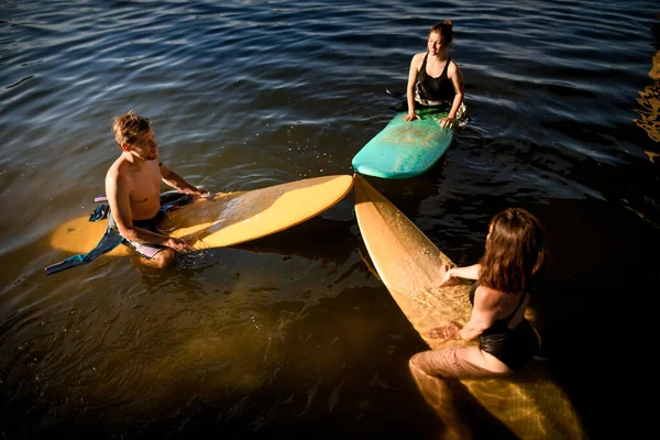 Grupo de personas se sientan en tablas de surf y se preparan para nadar — Foto de Stock