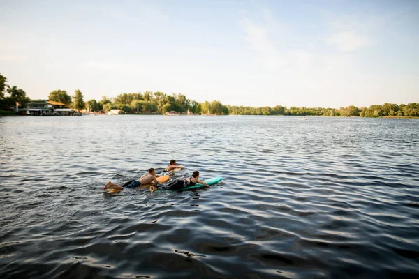 Pohled na skupinu lidí, kteří plují na surfařských prknech na říční vodě — Stock fotografie