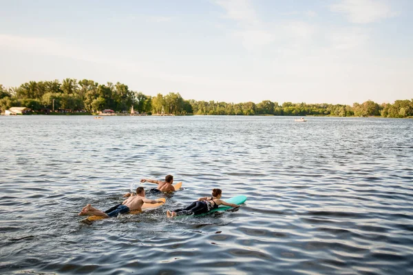 Vista trasera del grupo de atletas que flotan en tablas de surf en el agua del río —  Fotos de Stock