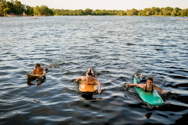 Vista frontal del grupo de personas que flotan en tablas de surf en el agua del río —  Fotos de Stock