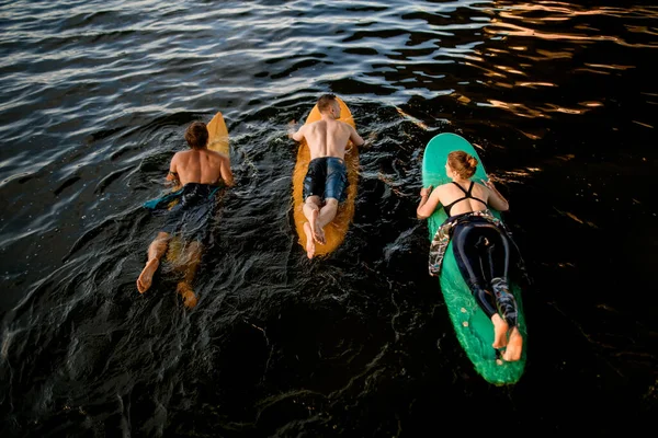 Vista superior del grupo de personas que flotan en tablas de surf en el agua del río —  Fotos de Stock