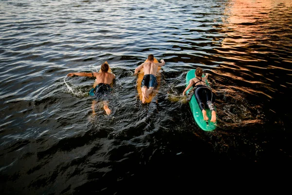 Vista superior del grupo de atletas que flotan en tablas de surf en el agua del río —  Fotos de Stock