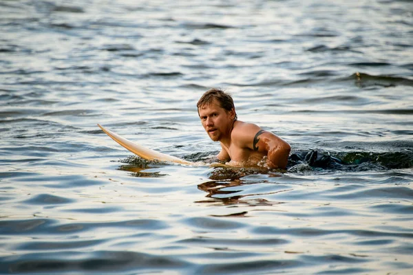 Mann liegt auf Surfbrett treibt auf Fluss. — Stockfoto
