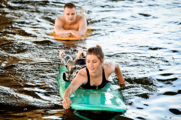 Hombre y mujer tumbados en tablas de surf flotan en el río . —  Fotos de Stock