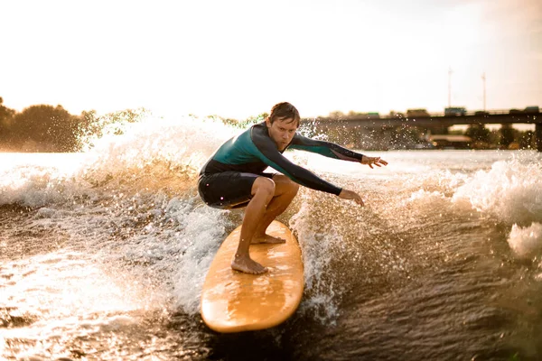 Activo joven atlético hombre despertar surfeando por las olas del río . —  Fotos de Stock